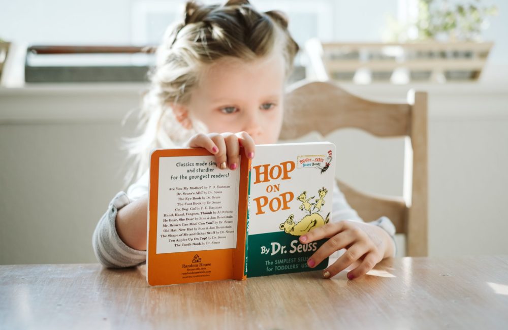 Petite fille lit un livre pour enfants Petite fille lit un livre jeunesse
